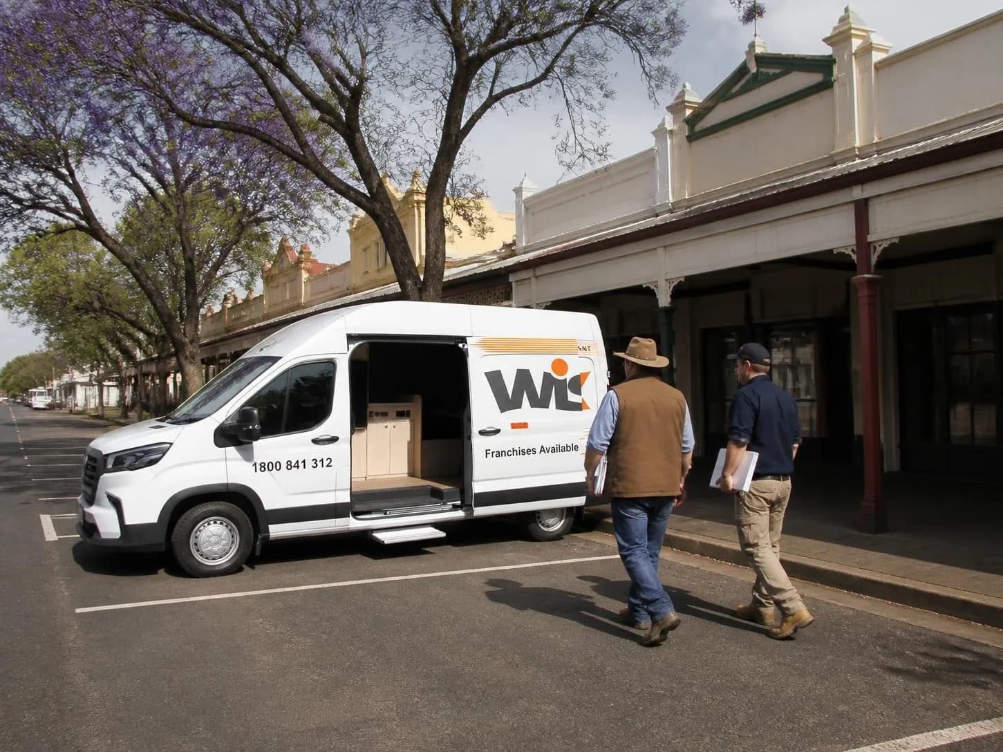 Mobile office van in operator livery, side door open, parked on a town street
